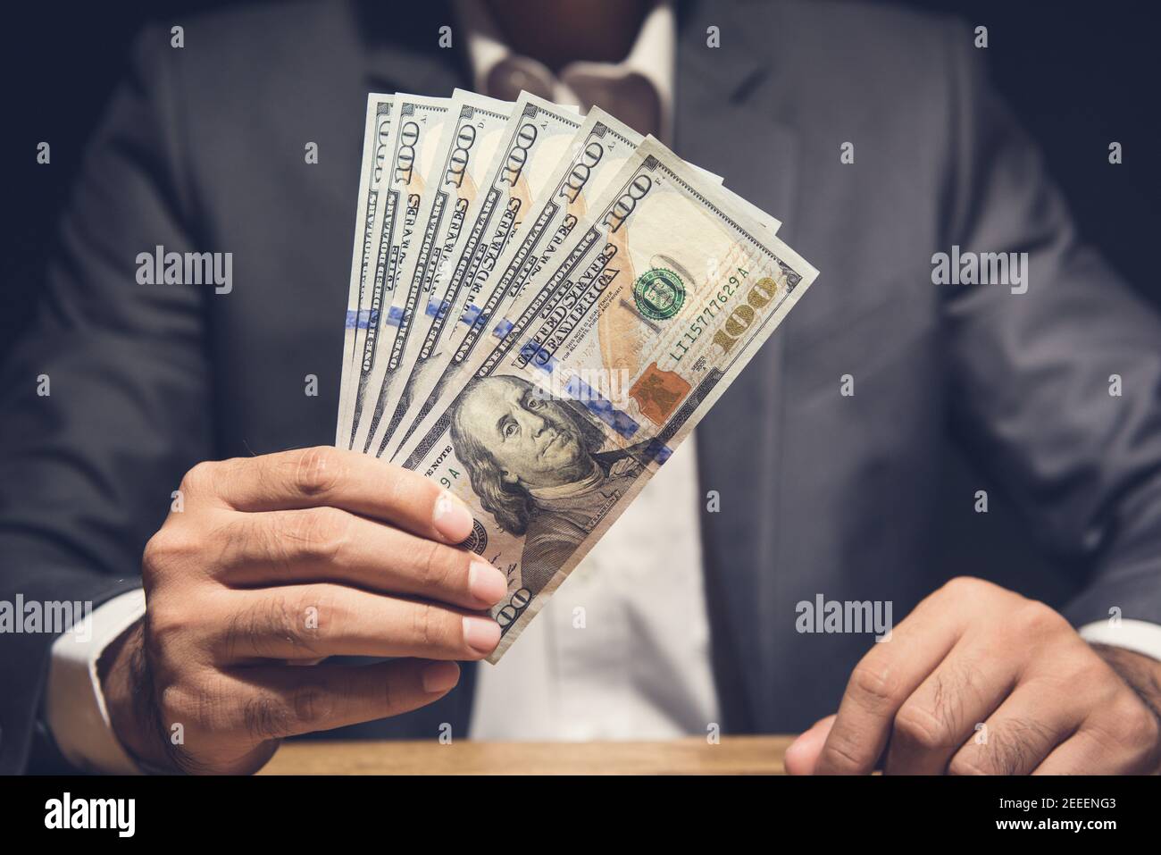 Businessman showing US dollar bills at the table in dark background - making money, bribery and venality concepts Stock Photo