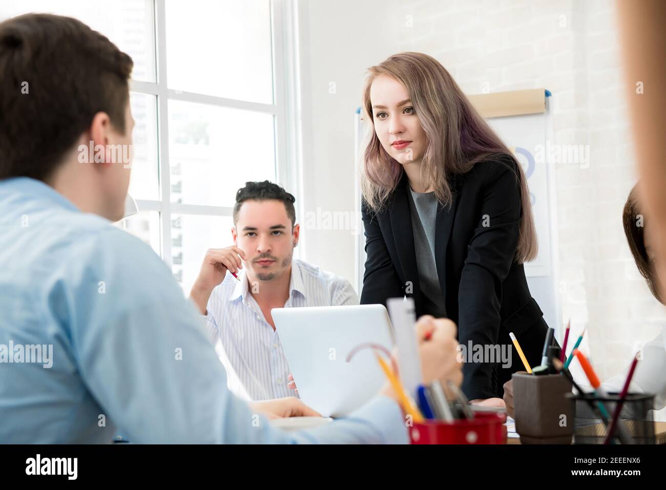 Female leader standing and paying attention to her colleague in the meeting Stock Photo