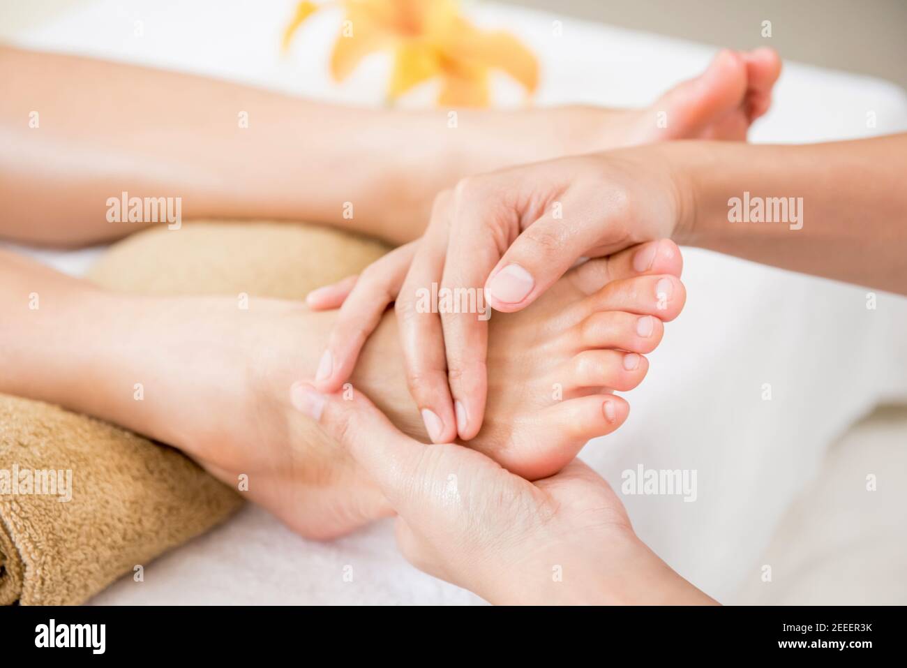 Professional therapist giving relaxing reflexology foot massage to a woman in spa Stock Photo