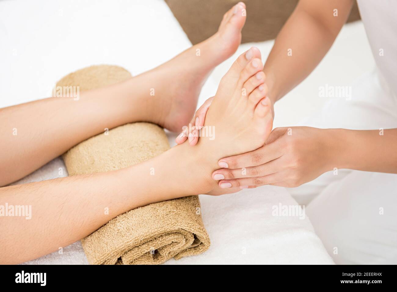 Professional therapist giving relaxing traditional thai reflexology foot massage to a woman in spa Stock Photo