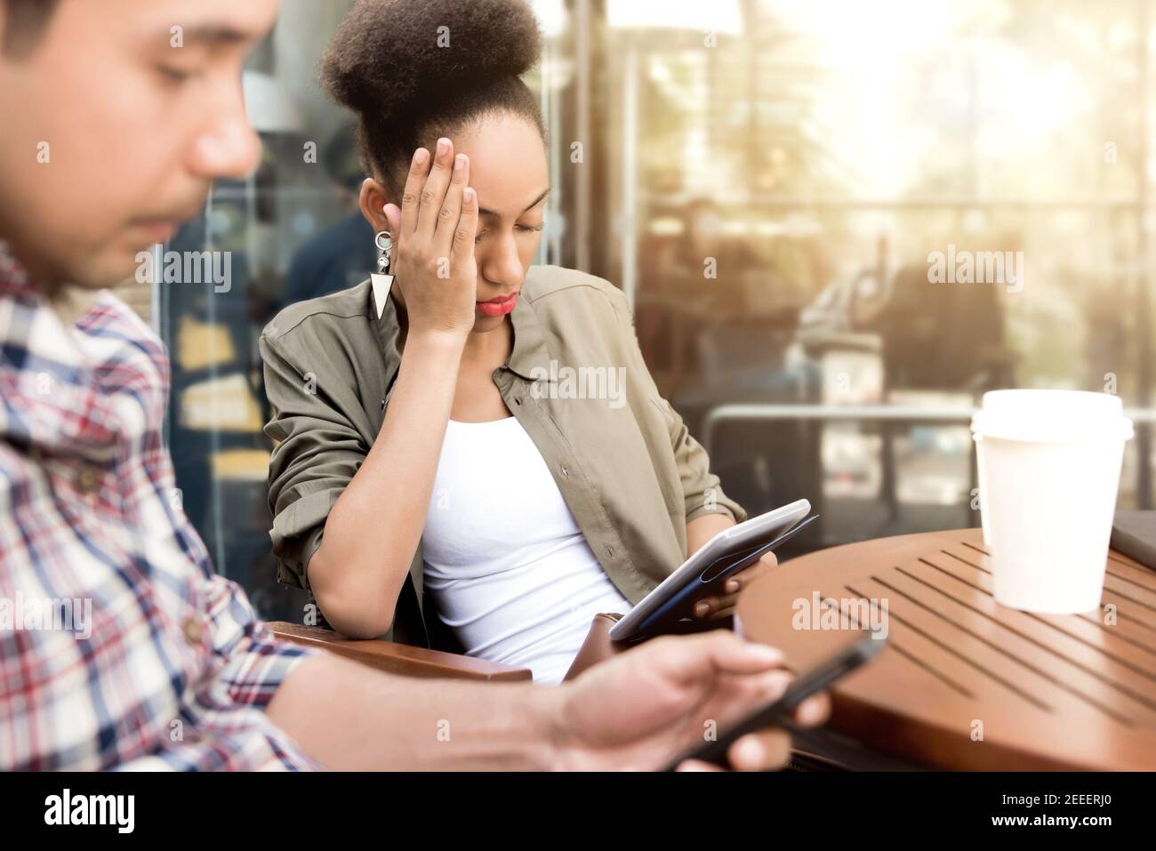 People seriously concentrating on using smartphone while sitting in coffee shop - social media addiction concept Stock Photo