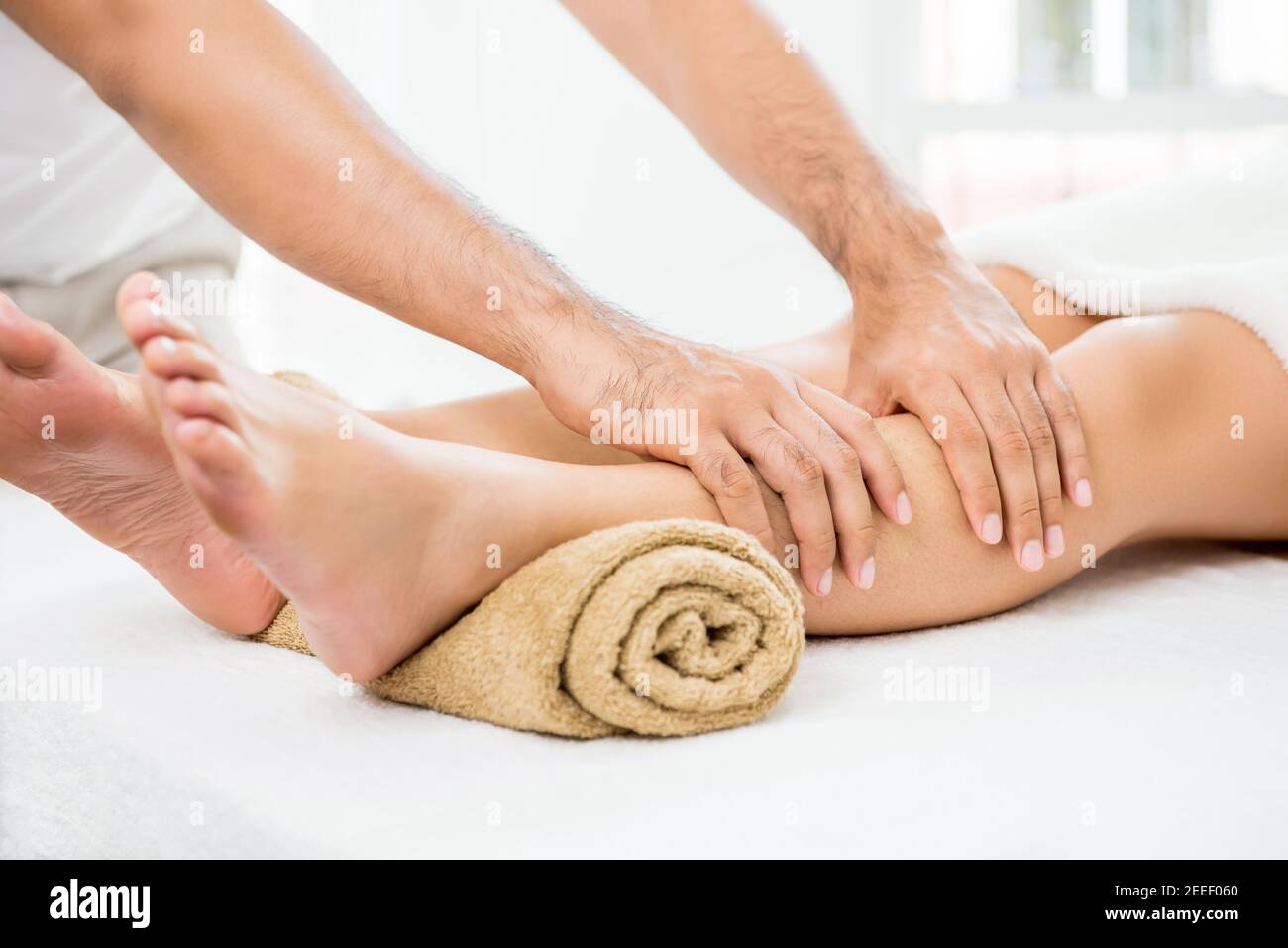 Hands of male therapist (masseur) giving massage to a woman leg Stock Photo