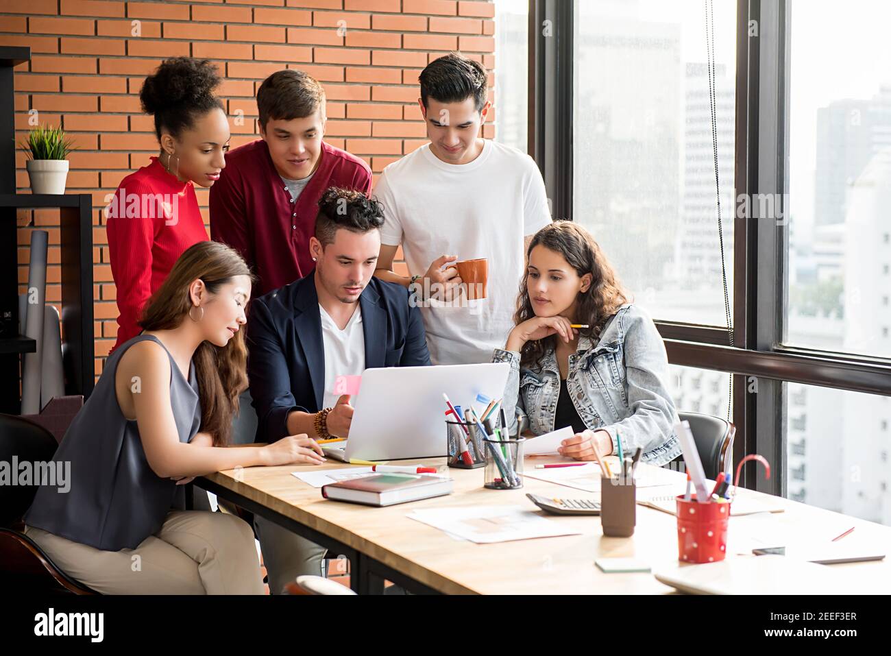 Multiethnic casual business team brainstorming in front of laptop computer Stock Photo