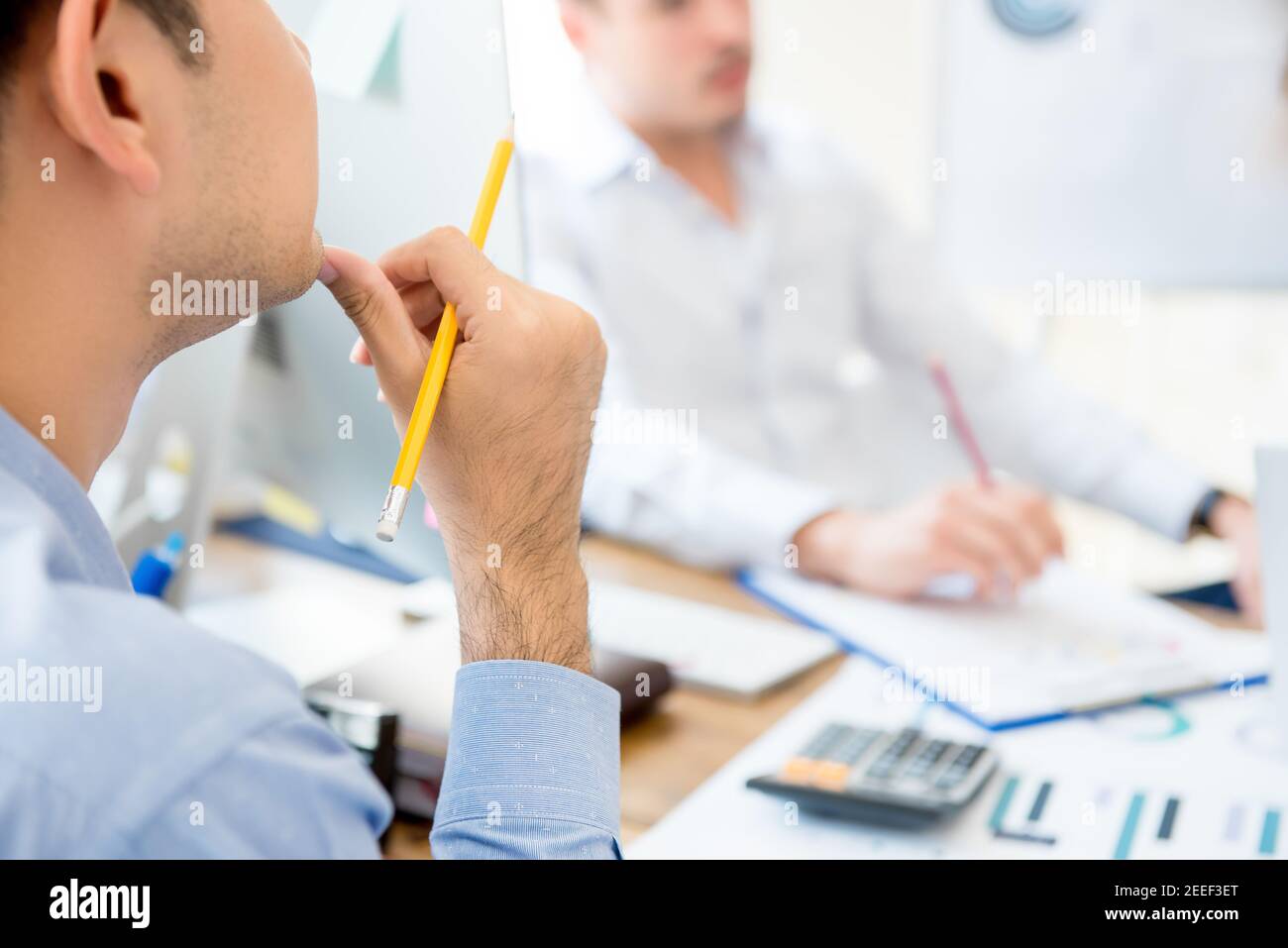 Businessman with hand on chin listening and paying attention to his colleague in the meeting Stock Photo