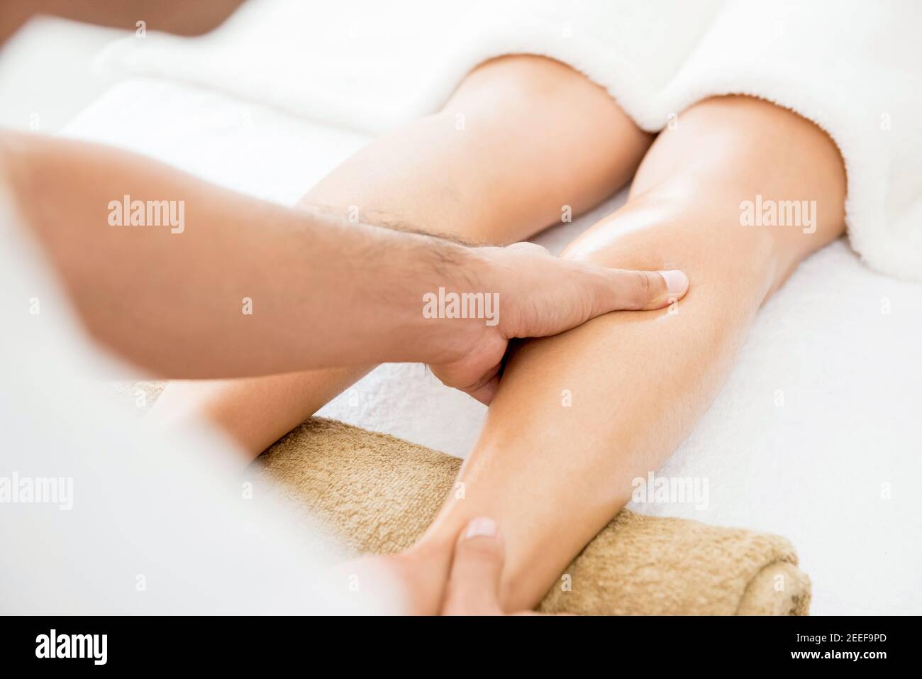 Male therapist (masseur) giving leg massage to a woman in spa Stock Photo