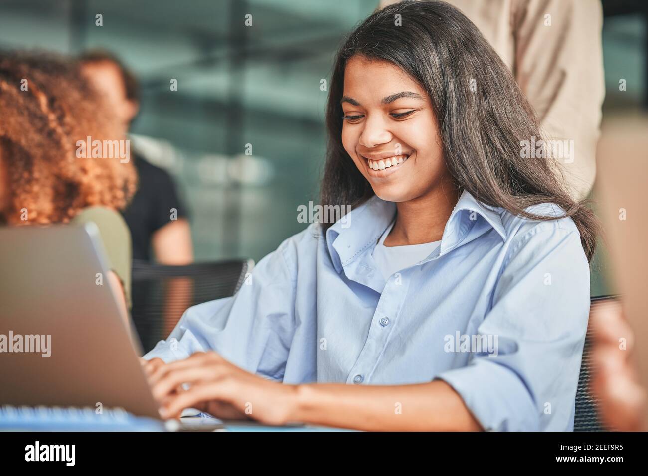 Cheerful young woman using her laptop and smiling Stock Photo