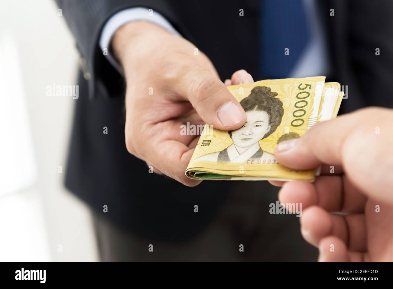 Businessman giving money, South Korean won banknotes, to his partner Stock Photo