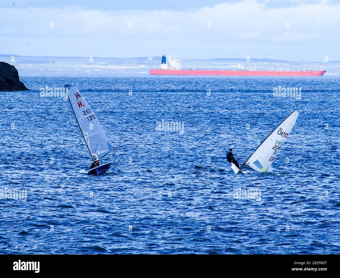 Two sailing dinghies with ship tanker in background Stock Photo Alamy