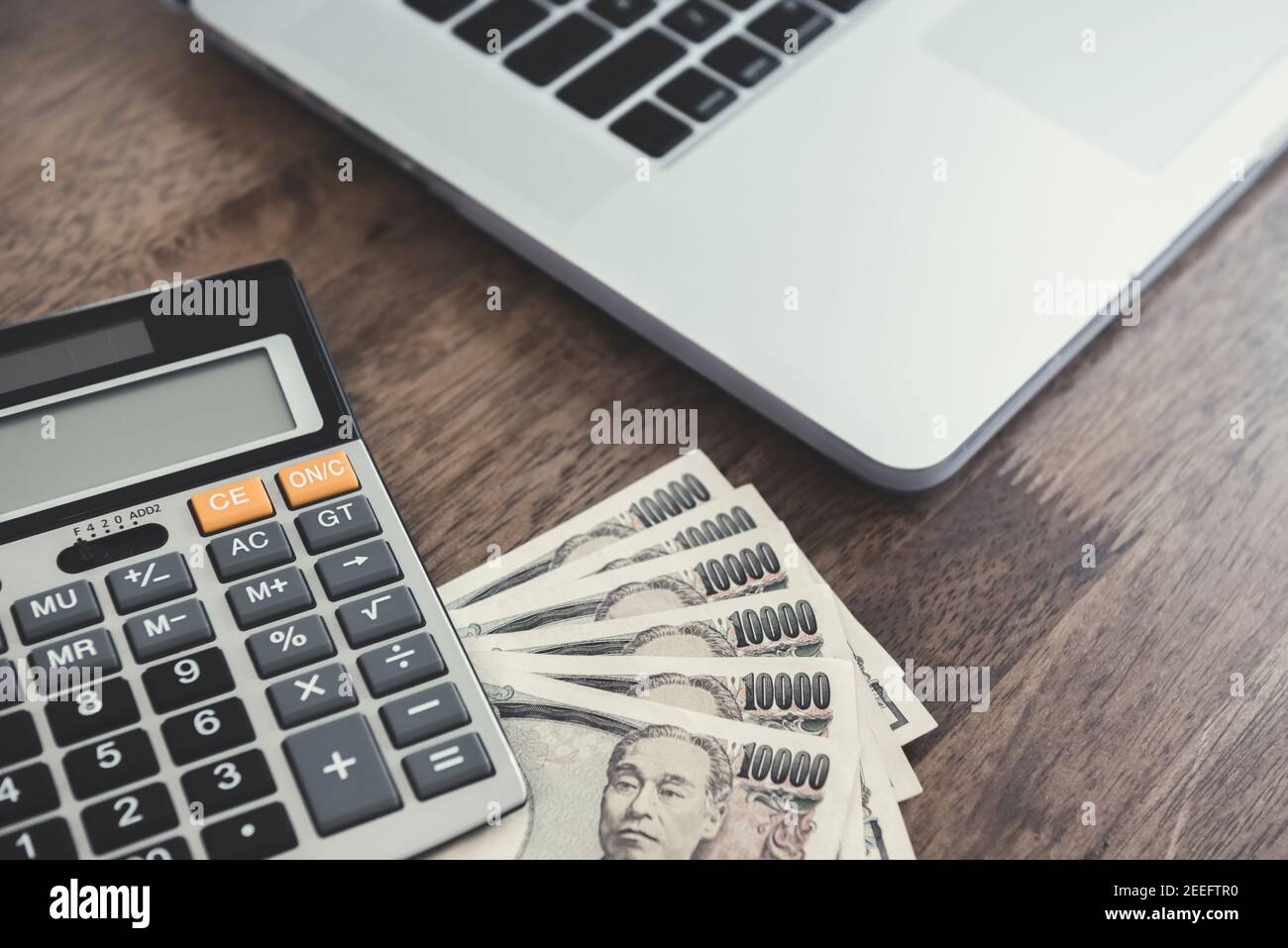 Money, Japanese yen banknotes, with calculator and notebook computer on wooden table Stock Photo