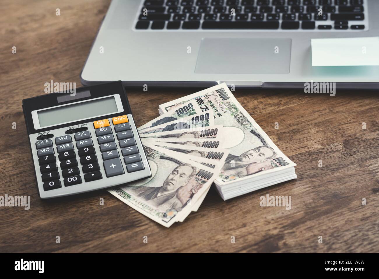 Money, Japanese yen banknotes, with calculator and notebook computer on wood table Stock Photo