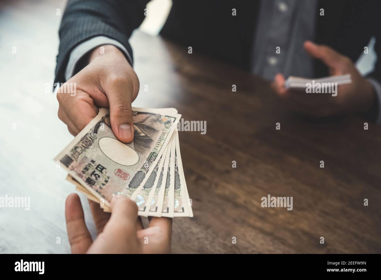 Businessman giving money, Japanese yen banknotes, to his partner - payment, loan and bribery concepts Stock Photo