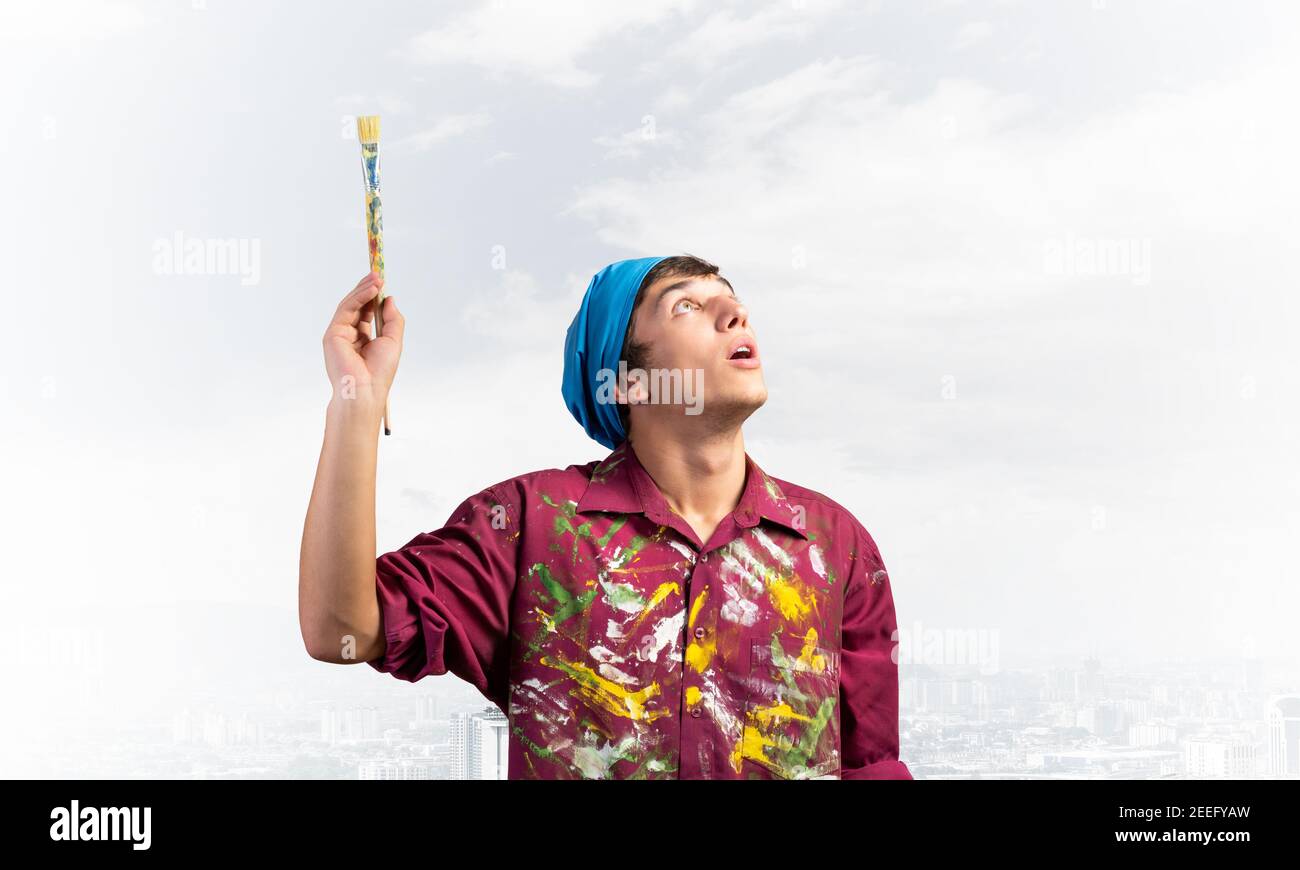 Young painter artist holding paint brush overhead Stock Photo Alamy