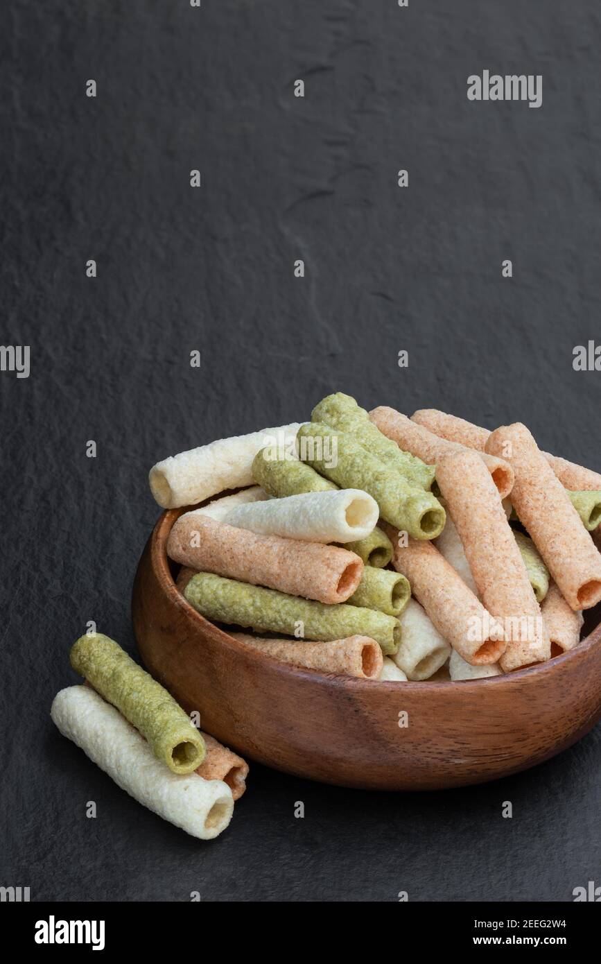 Pea and bean sticks in wooden bowl on black stone background Stock