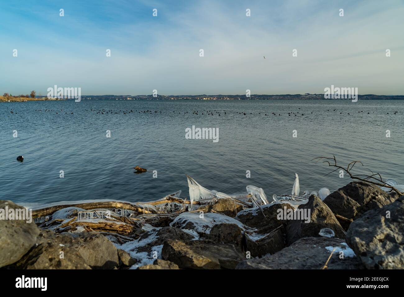 Tench holes in the morning light in winter cold. Shore of Lake Constance with natural ice created sculptures. german shore with Lindau  in Background Stock Photo