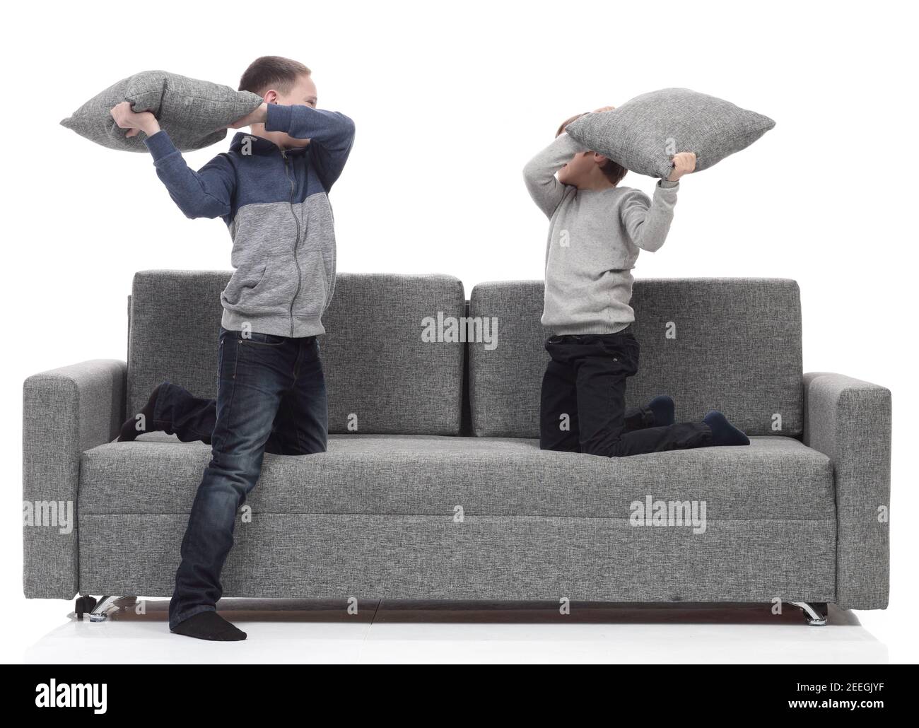 two brothers have a pillow fight on the couch. Stock Photo