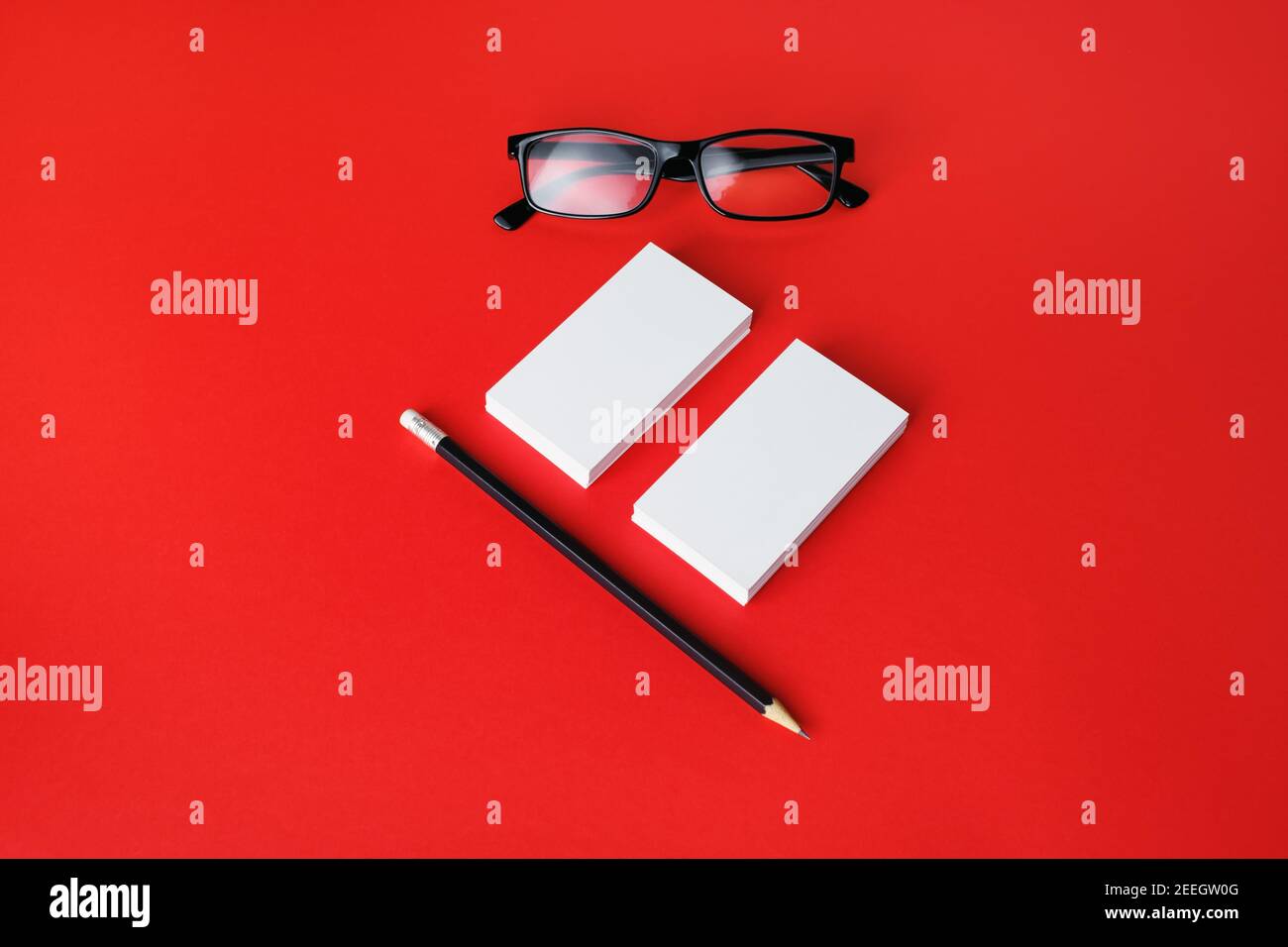 Blank business cards, pencil and glasses on red paper background. Branding mock up. Stock Photo