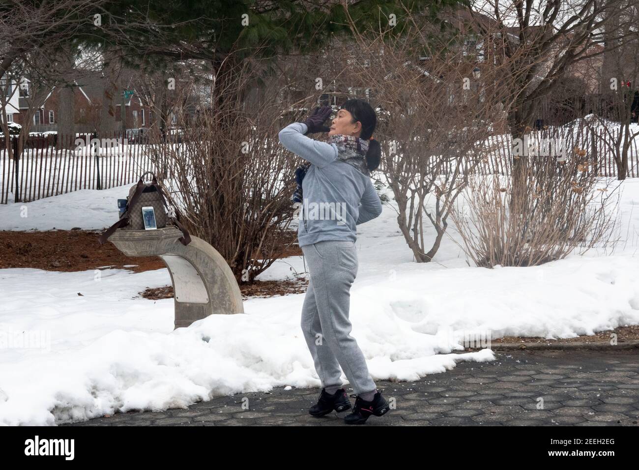 On a cold winter morning, a Chinese American woman dances & exercises to music from her iphone. In Flushing, Queens, New York City. Stock Photo