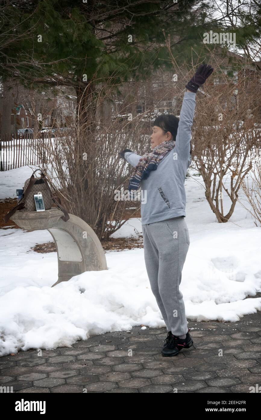 On a cold winter morning, a Chinese American woman dances & exercises to music from her iphone. In Flushing, Queens, New York City. Stock Photo