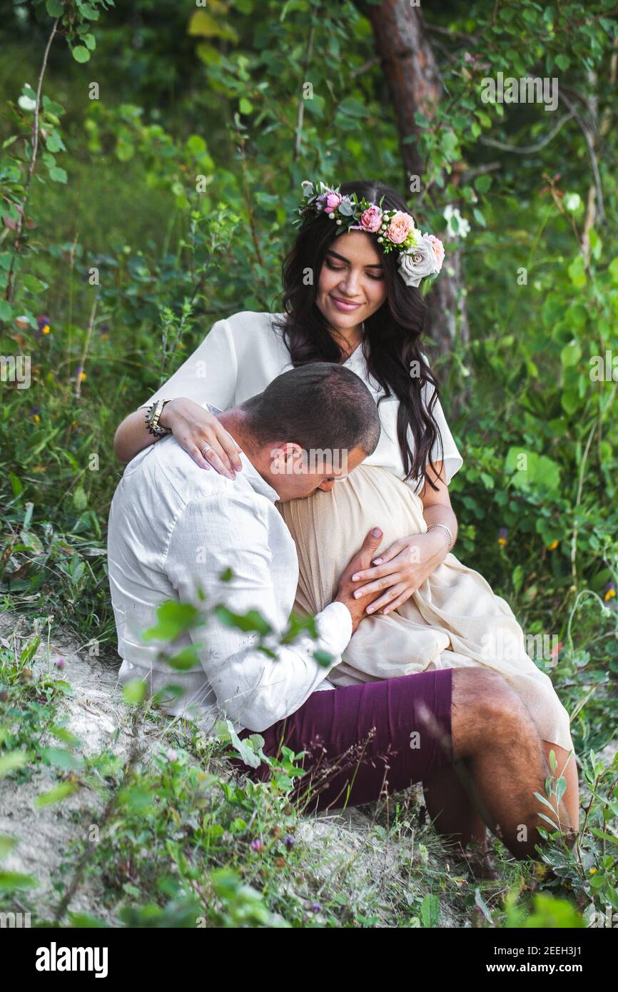 Young pregnant woman with her husband enjoying the nature wearing casual and style jeans and white t-shirt. Stock Photo