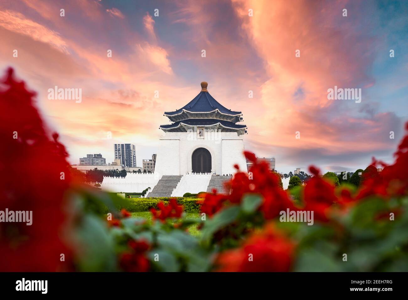 (Selective focus) Stunning view of the National Chiang Kai-shek Memorial Hall in the background and blurred red flowers in the foreground. Stock Photo