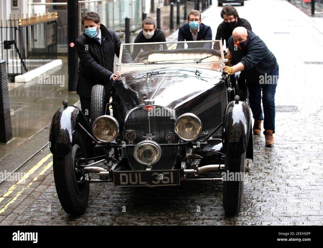 London, UK 16 Feb 2021 Bonhams staff wheel the Bugatti into the showroom. 1937 Bugatti Type 57S offered for the first time ever at auction, estimate £5-7 Million. This classic car will lead an extraordinary sale of exceptional motor cars at Bonhams' flagship saleroom in London on 19 February 2021. Nicknamed ‘Dulcie' due to its registration number ‘DUL 351' - it has been stored in the garage of its late owner, respected engineer Bill Turnbull, since 1969, and is now offered as an unfinished project, at no reserve. Estimate £5,000,000 - 7,000,000. The Bugatti will form the centrepiece of the Stock Photo