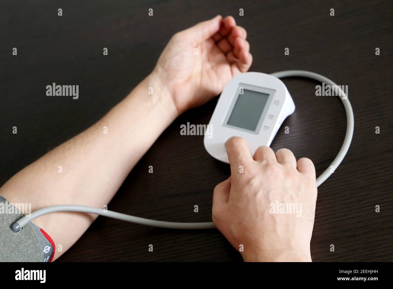 Male hands with blood pressure monitor, man measuring the pressure. Health care and cardiology concept Stock Photo