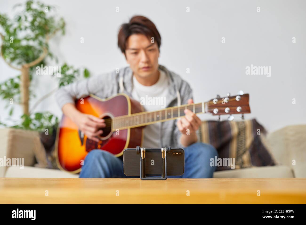 Japanese man playing guitar at home Stock Photo