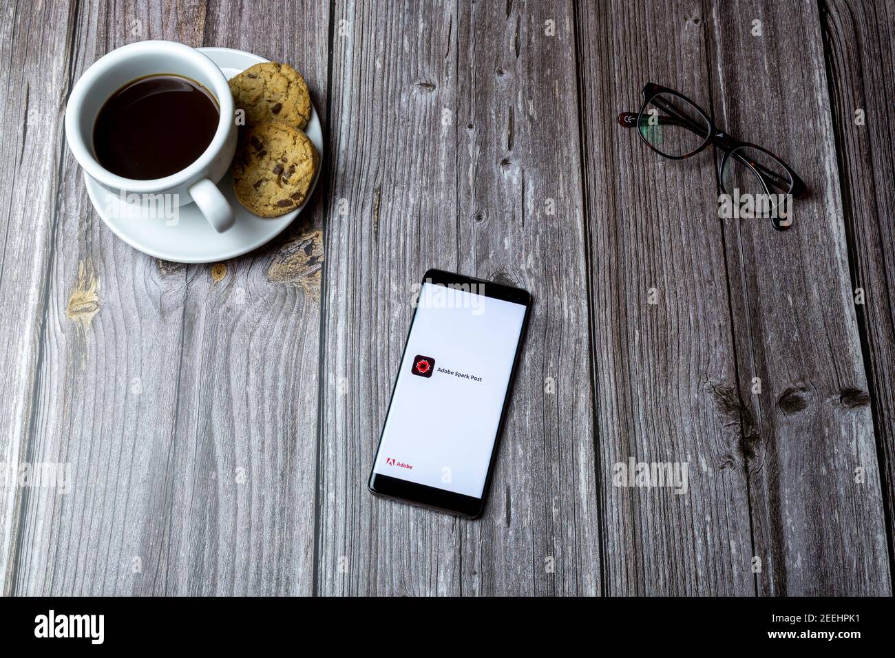 A mobile phone or cell phone laid on a wooden table with the adobe spark app open on screen Stock Photo