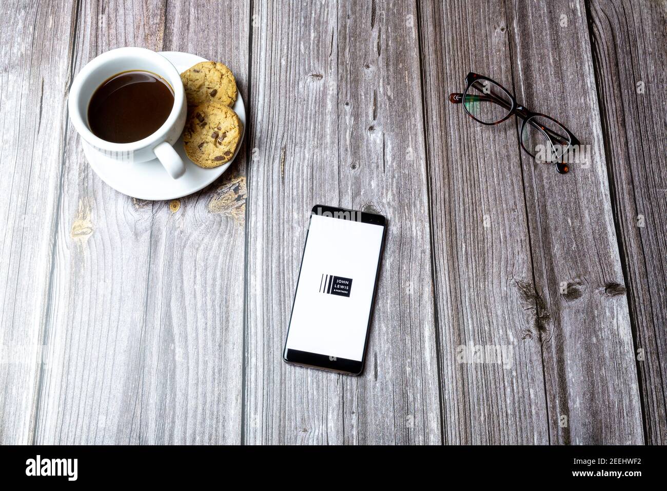 A mobile phone or cell phone laid on a wooden table with the John lewis and partners app open on screen Stock Photo