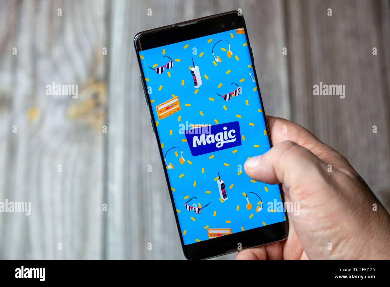A mobile phone or cell phone being held in a hand with the Magic Radio app open on screen Stock Photo