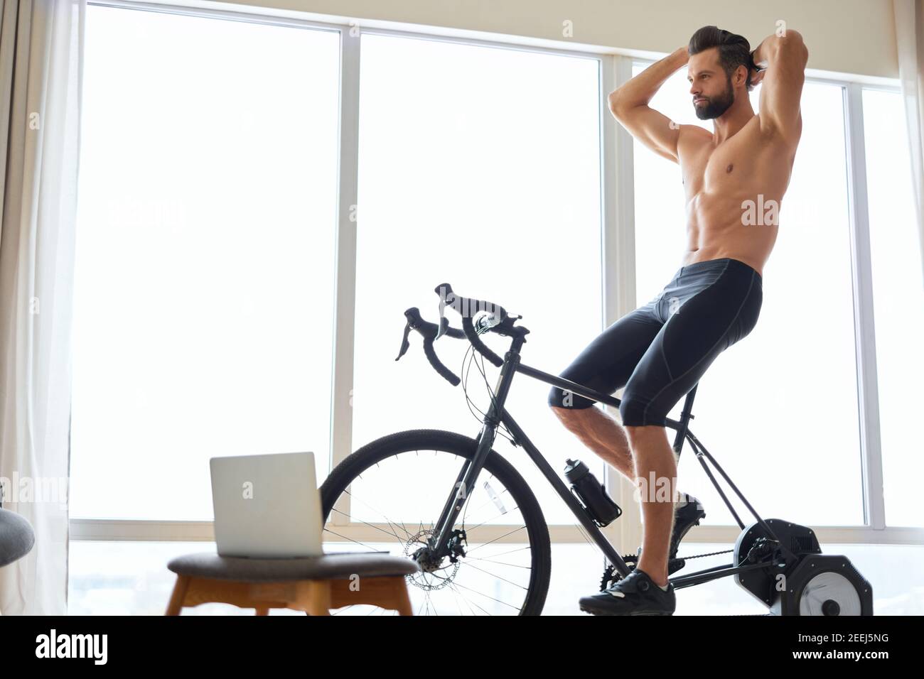Handsome muscular gentleman with perfect body riding exercise bicycle ...
