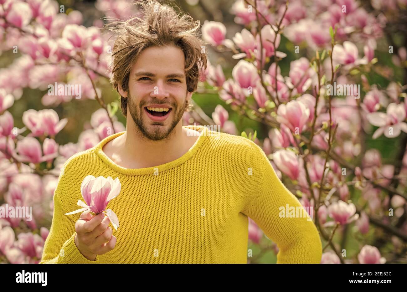 Hairdo styling. Floral cosmetics concept. Hipster enjoy blossom aroma ...
