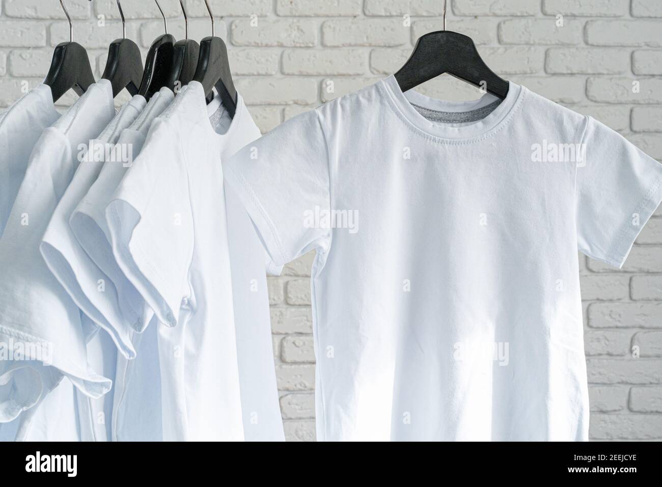 White t-shirt hanging on hanger against brick wall Stock Photo