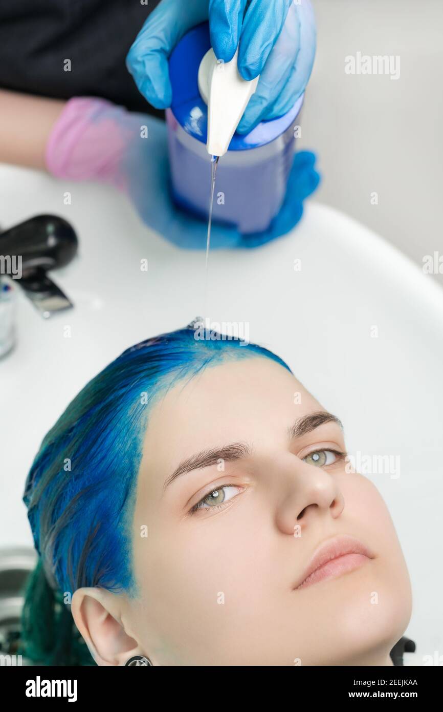 Closeup view of hairdresser hands in gloves squeezes shampoo and