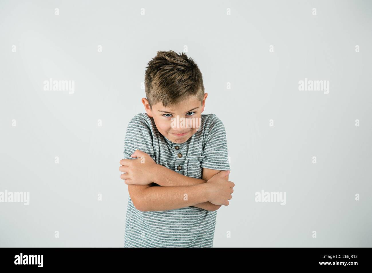 Little caucasian boy standing in a studio setting on a white backdrop. Stock Photo