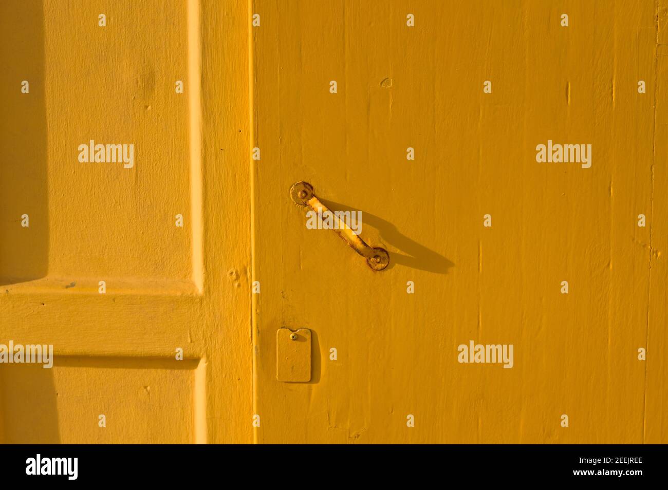 A yellow wooden door background with a rusted iron handle (Pesaro, Italy, Europe) Stock Photo