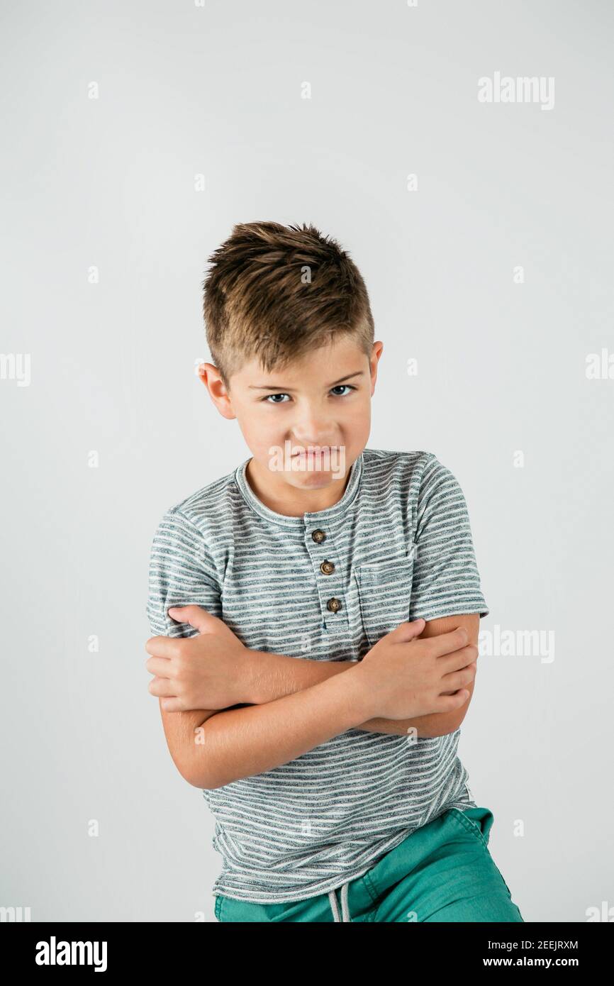 Little caucasian boy standing in a studio setting on a white backdrop. Stock Photo