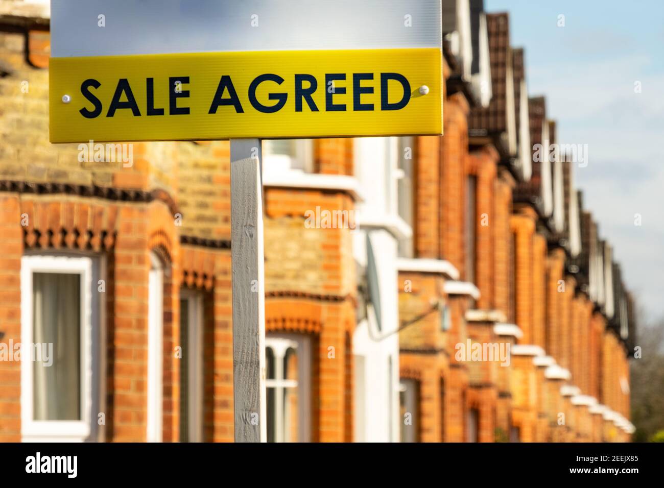 Estate agent sale agreed sign on street of terraced houses Stock Photo