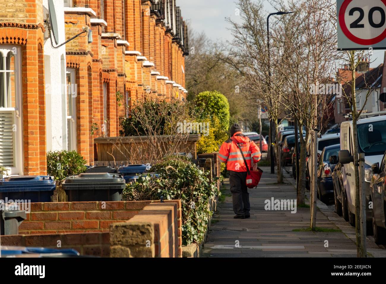 London- Postman on residential street of terraced houses in Northfields, Ealing West London Stock Photo