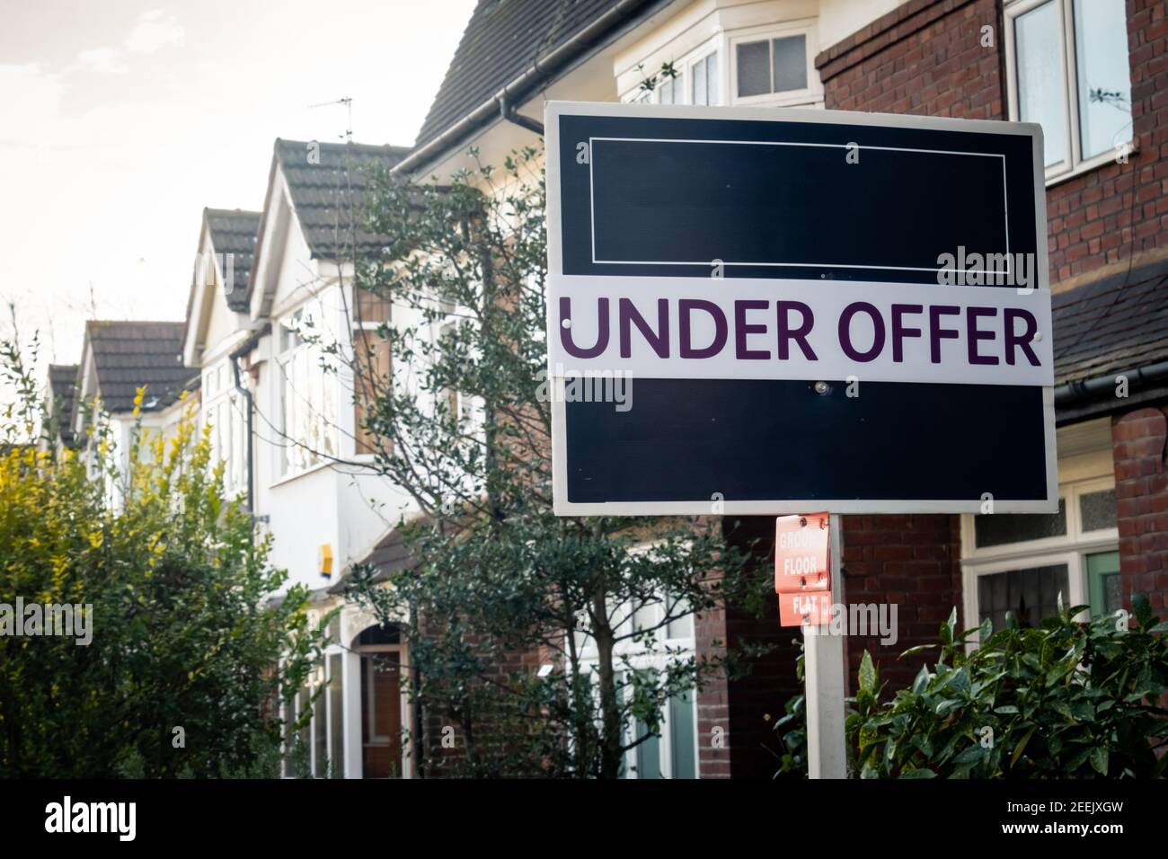 Estate agent 'Under Offer' sign on street of suburban British houses Stock Photo