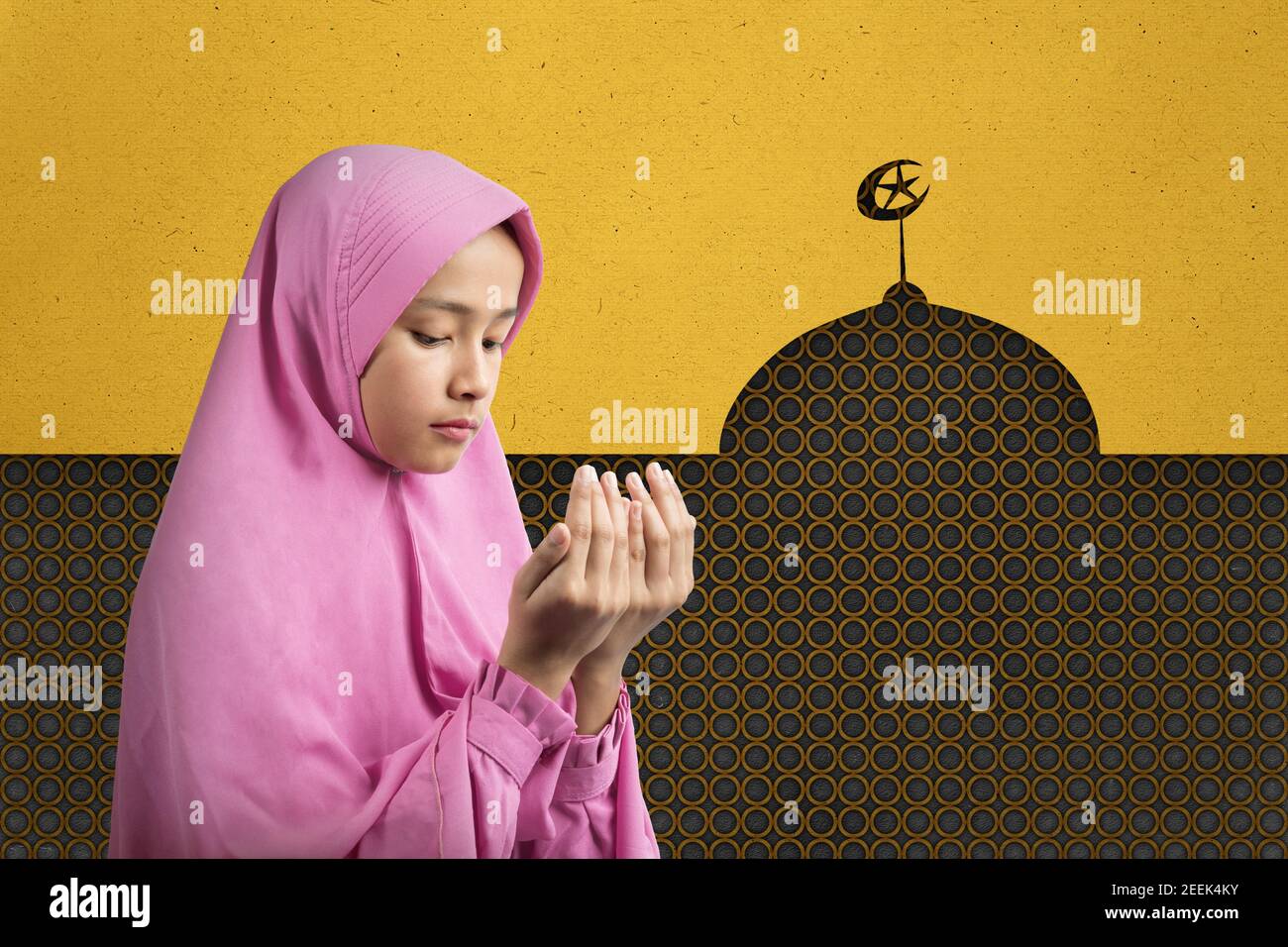 Asian Muslim woman in a veil standing while raised hands and praying ...