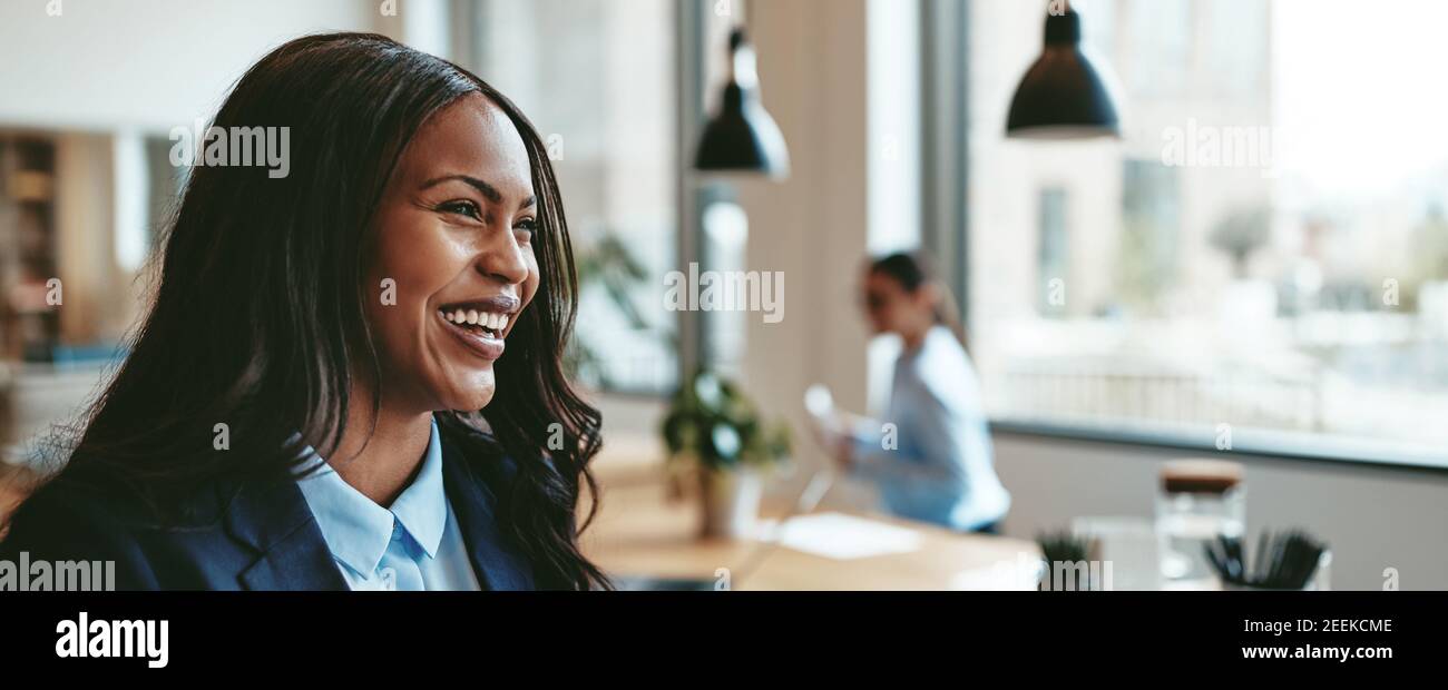 Young African American businesswoman laughing while walking in an office after a meeting with colleagues Stock Photo