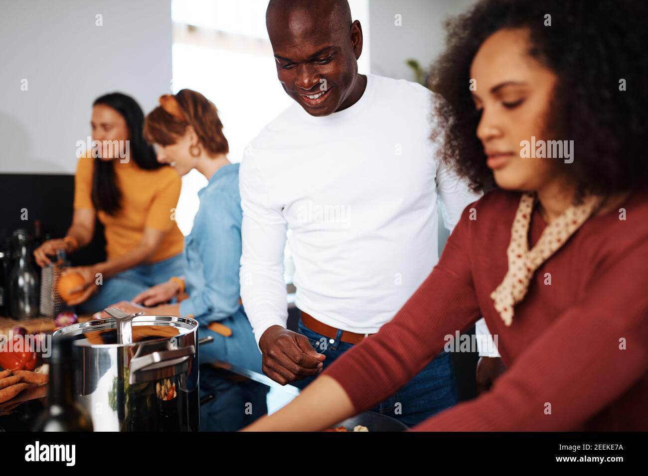 Smiling young African American man helping his friend with cooking while preparing for a dinner party with friends Stock Photo