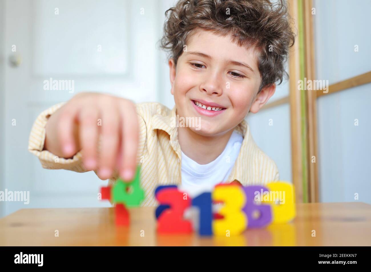 Cute little boy puts wooden numbers on the table Stock Photo
