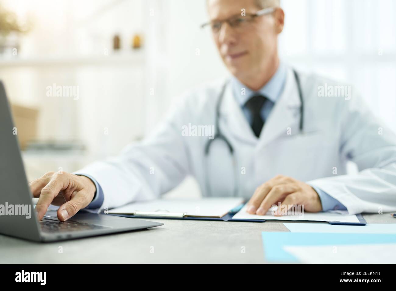 Handsome doctor using modern notebook in clinic Stock Photo