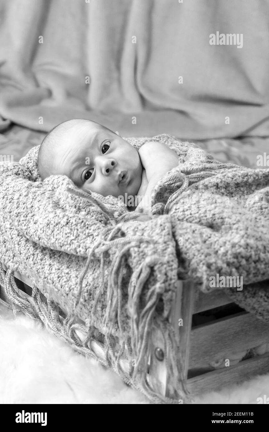 Black and white photo of a newborn with an emotional expression on his face. Selective focus with shallow depth of field. Stock Photo