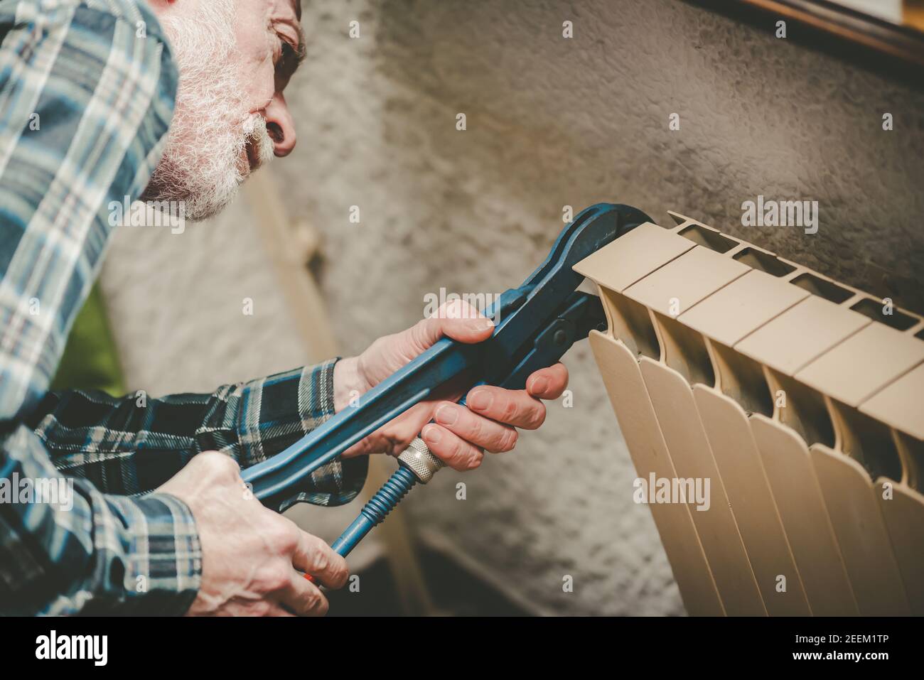 Repairman working on radiator with wrench Stock Photo - Alamy
