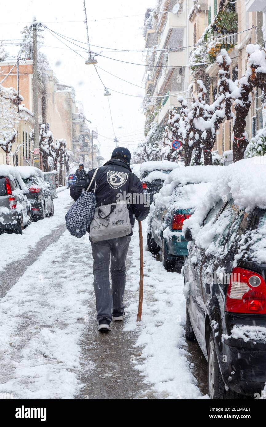 Man walking carefully on wet asphalt road during snowfall in Athens city, capital of Greece, Europe Stock Photo