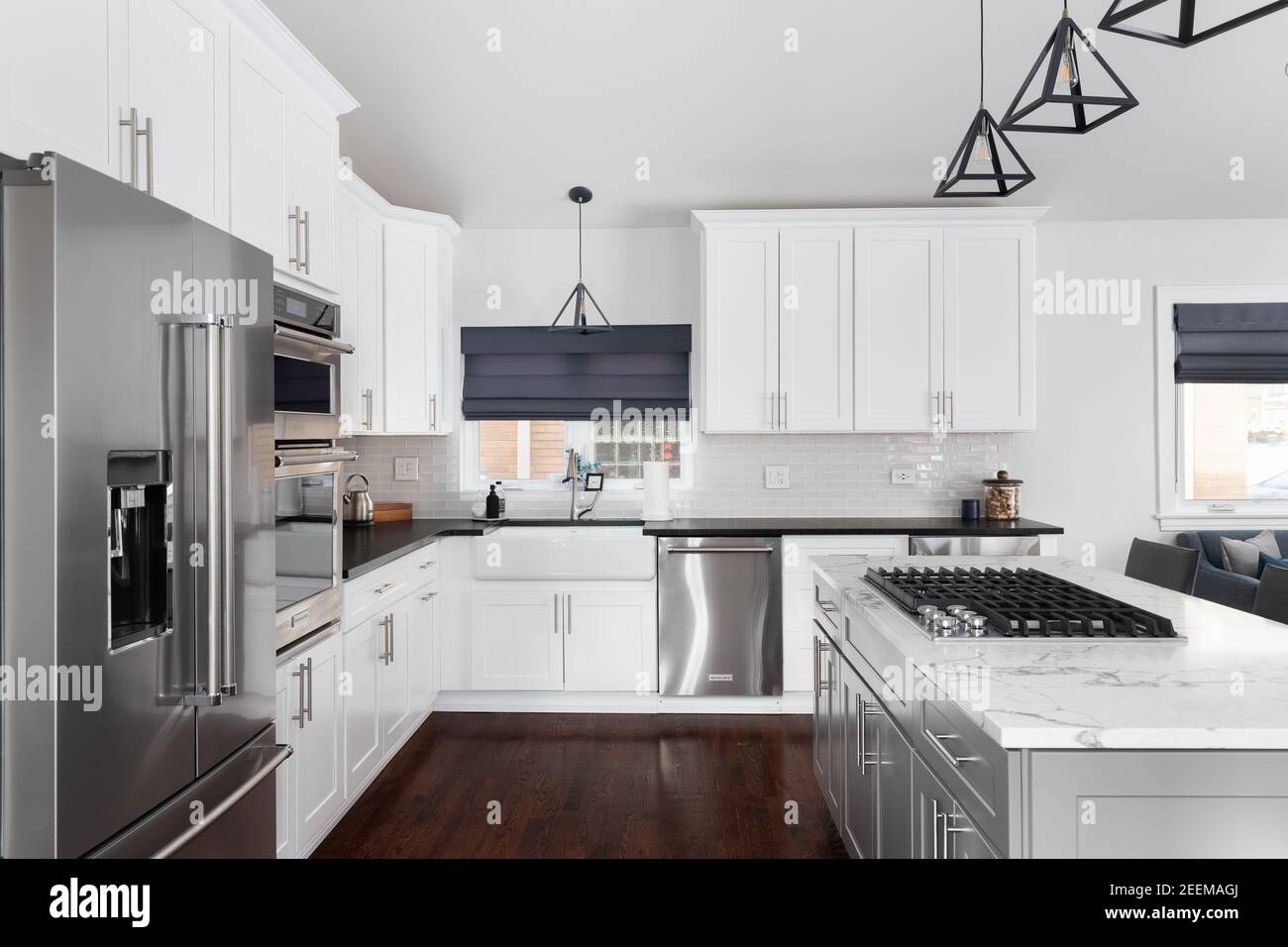 A beautiful white kitchen in a modern farmhouse with black lights ...