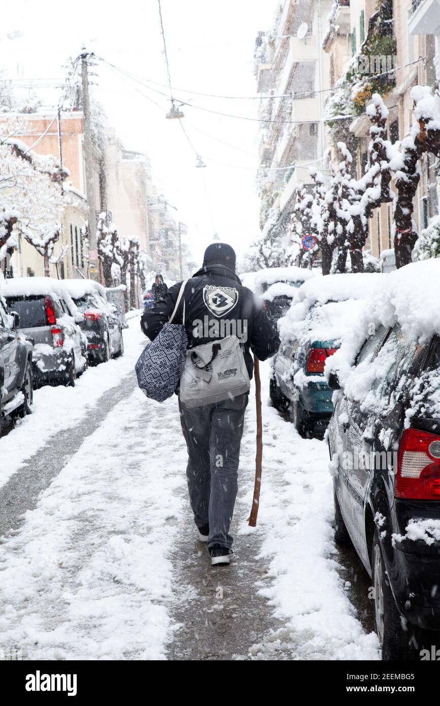 Man walking carefully on wet asphalt road during snowfall in Athens city, capital of Greece, Europe Stock Photo